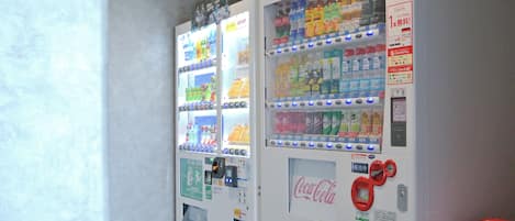 Two Coca-Cola vending machines with various beverage options and a payment interface.