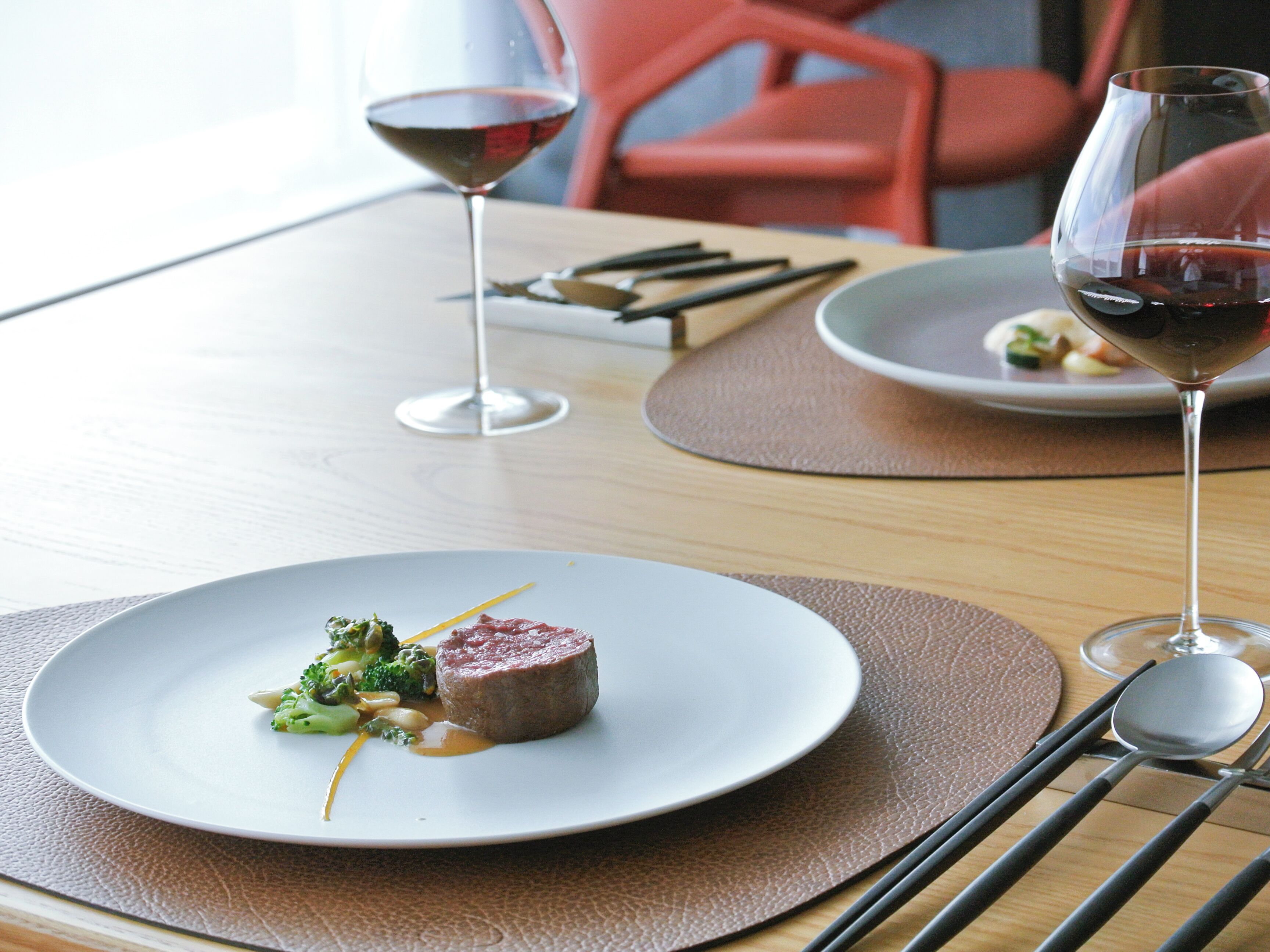 A dining table with plates of food, cutlery, and wine glasses.
