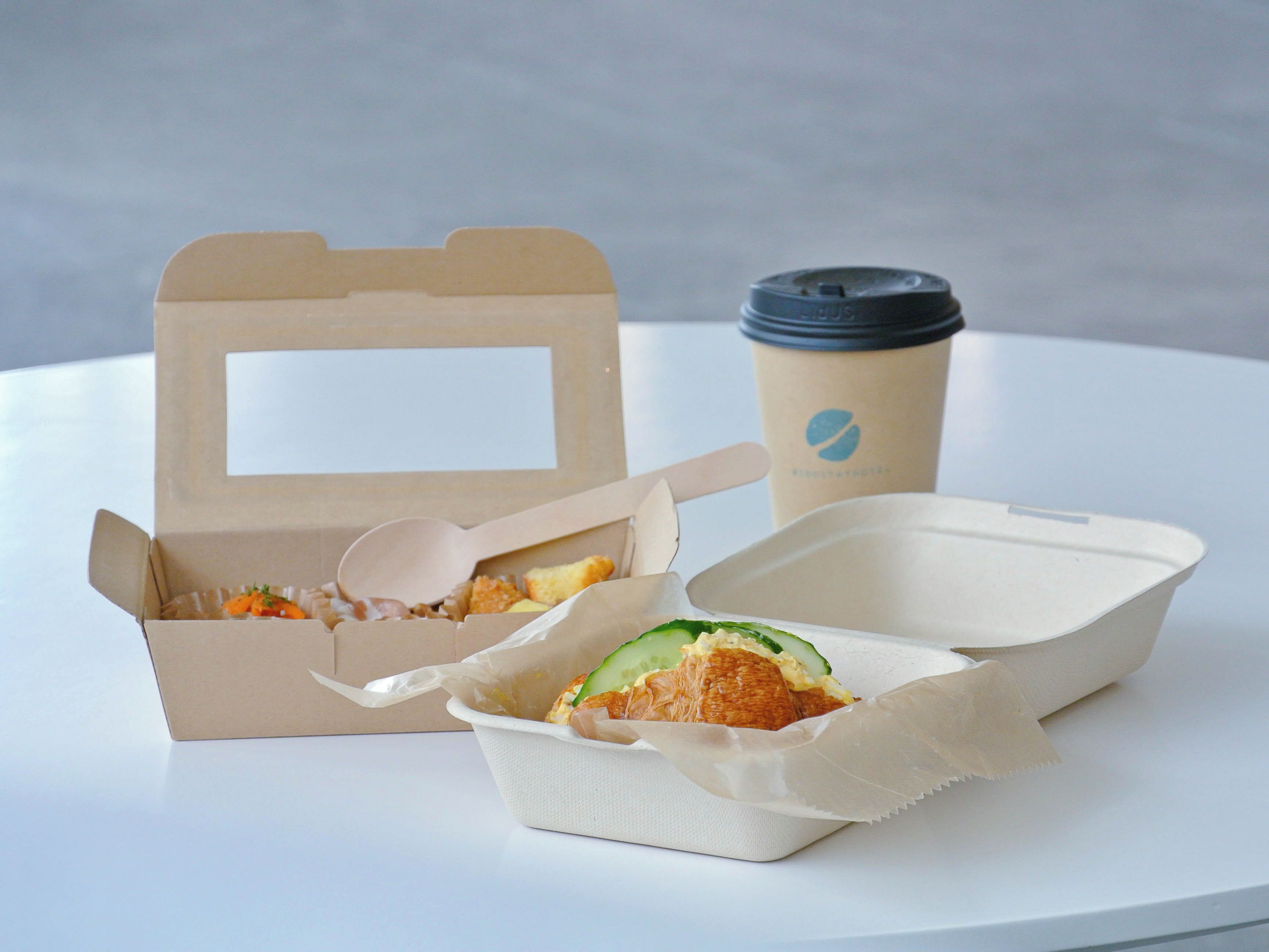 A takeaway meal with a wooden spoon and a cup with a lid.