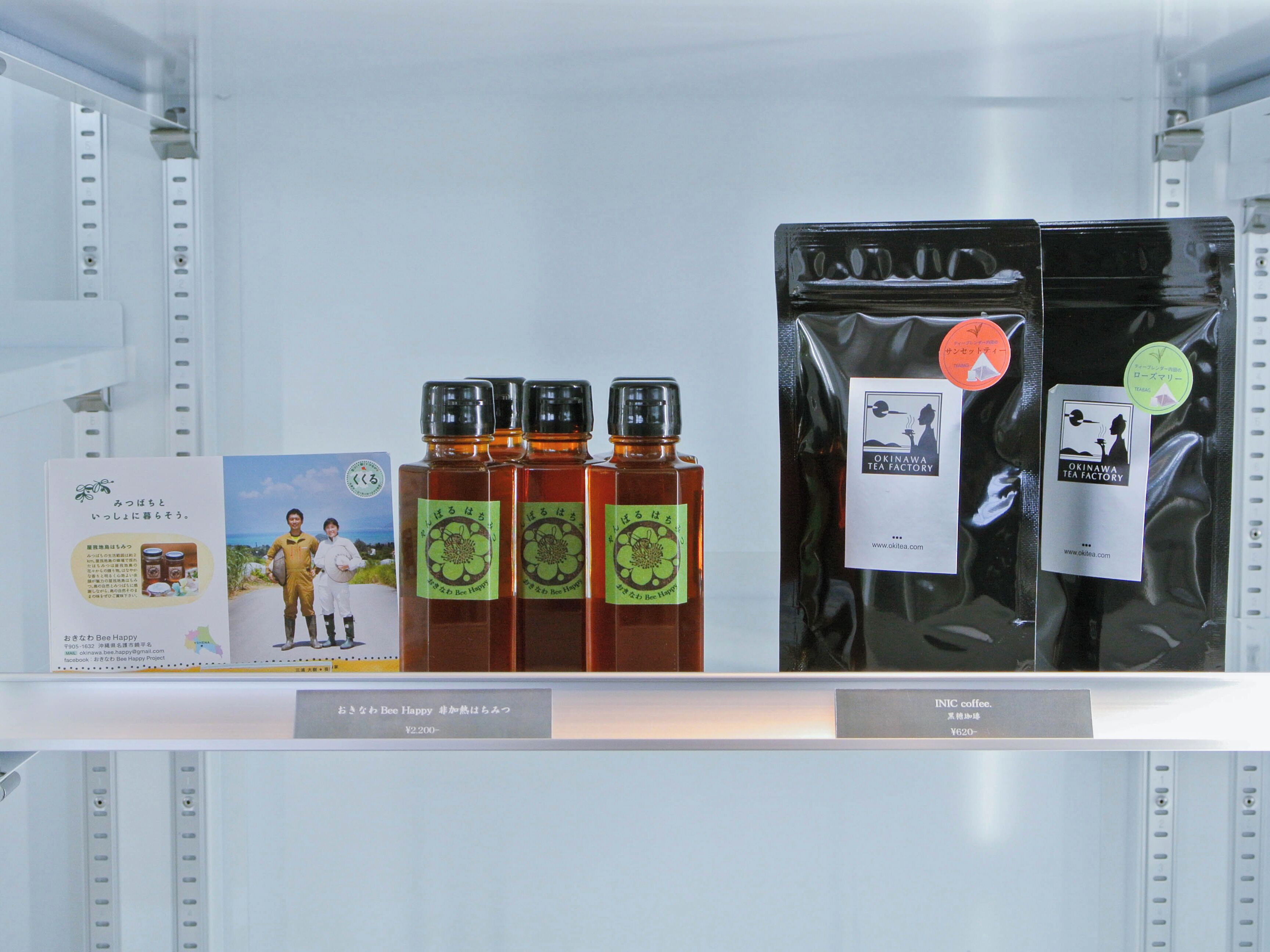 Una estantería exhibe tres botellas de té y dos paquetes de café.