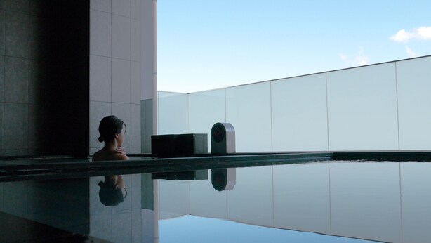 A woman in a reflective pool with a digital clock displaying 4:21. - ASBO STAY HOTEL (Kin)