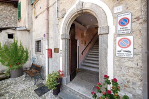 Une entrée en pierre, avec un banc, des plantes en pot et un escalier menant à l’intérieur du bâtiment.
