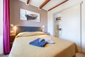 Una camera d'albergo con un letto, un quadro, una porta e un comodino.