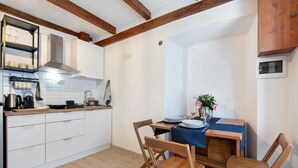 A compact kitchen with white cabinets, a wooden dining table, and a built-in stove. - Holiday Apartment "Taronico Heron" with Lake View, Shared Terrace & Wi-Fi (bellagio)