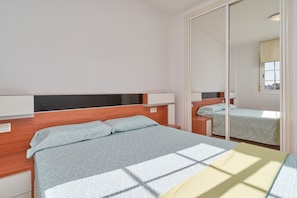 A bedroom with a bed, bedside tables, a mirror, and a wardrobe. - Holiday Home 'Del Mar Salobreña' with Shared Pool, Private Terrace and Shared Garden (Salobreña)