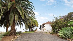 A gravel driveway leading to a building with a tiled roof, surrounded by palm trees and various plants. - Holiday Home 'Casa Rural Ciso' with Sea View, Private Garden and Wi-Fi (tijarafe)