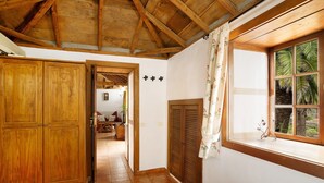 A room with wooden ceiling beams, a window with curtains, a wooden wardrobe, and a tiled floor. - Holiday Home 'Casa Rural Ciso' with Sea View, Private Garden and Wi-Fi (tijarafe)