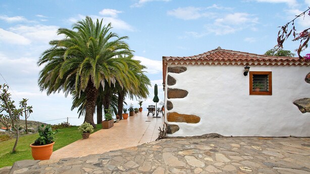 A white building with a tiled roof, a stone pathway, and a palm tree. - Holiday Home 'Casa Rural Ciso' with Sea View, Private Garden and Wi-Fi (tijarafe)
