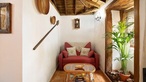 A cozy living room with a red sofa, a wooden ceiling, a wall-mounted clock, and a potted plant. - Holiday Home 'Casa Rural Ciso' with Sea View, Private Garden and Wi-Fi (tijarafe)