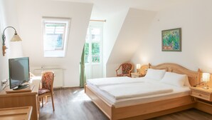 Une chambre à coucher comprenant un lit, des tables de chevet, un bureau avec une chaise, une télévision et une fenêtre.