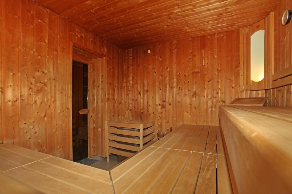 Un sauna en bois, doté de bancs et d’une banquette.