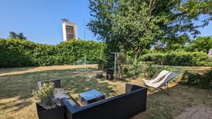 Un espace patio aménagé avec un canapé d’extérieur noir, un hamac et une petite table.