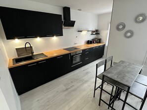 Une cuisine moderne avec des meubles de couleur noire, un plan de travail en bois et un four encastré.
