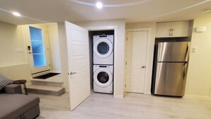 Un espacio habitable pequeño con lavadora, refrigerador y sofá.