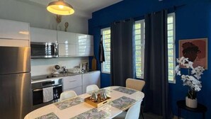 A modern kitchen with stainless steel appliances, a dining area with a table and chairs, and a blue accent wall.