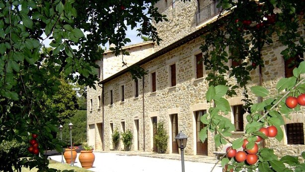 Un edificio de piedra con un patio, plantas en macetas grandes y un farol.