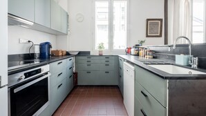 Une cuisine de taille réduite, équipée d’une cuisinière, d’un four et d’un évier. On y trouve également des placards, une fenêtre et une plante.