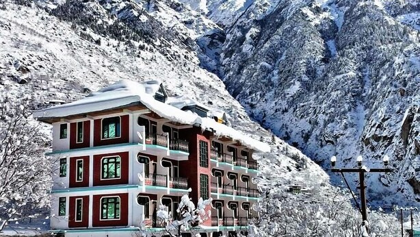 A hotel with multiple floors, balconies, and a view of snow-covered mountains. - Hotel Prakash Regency Sangla (Sangla)