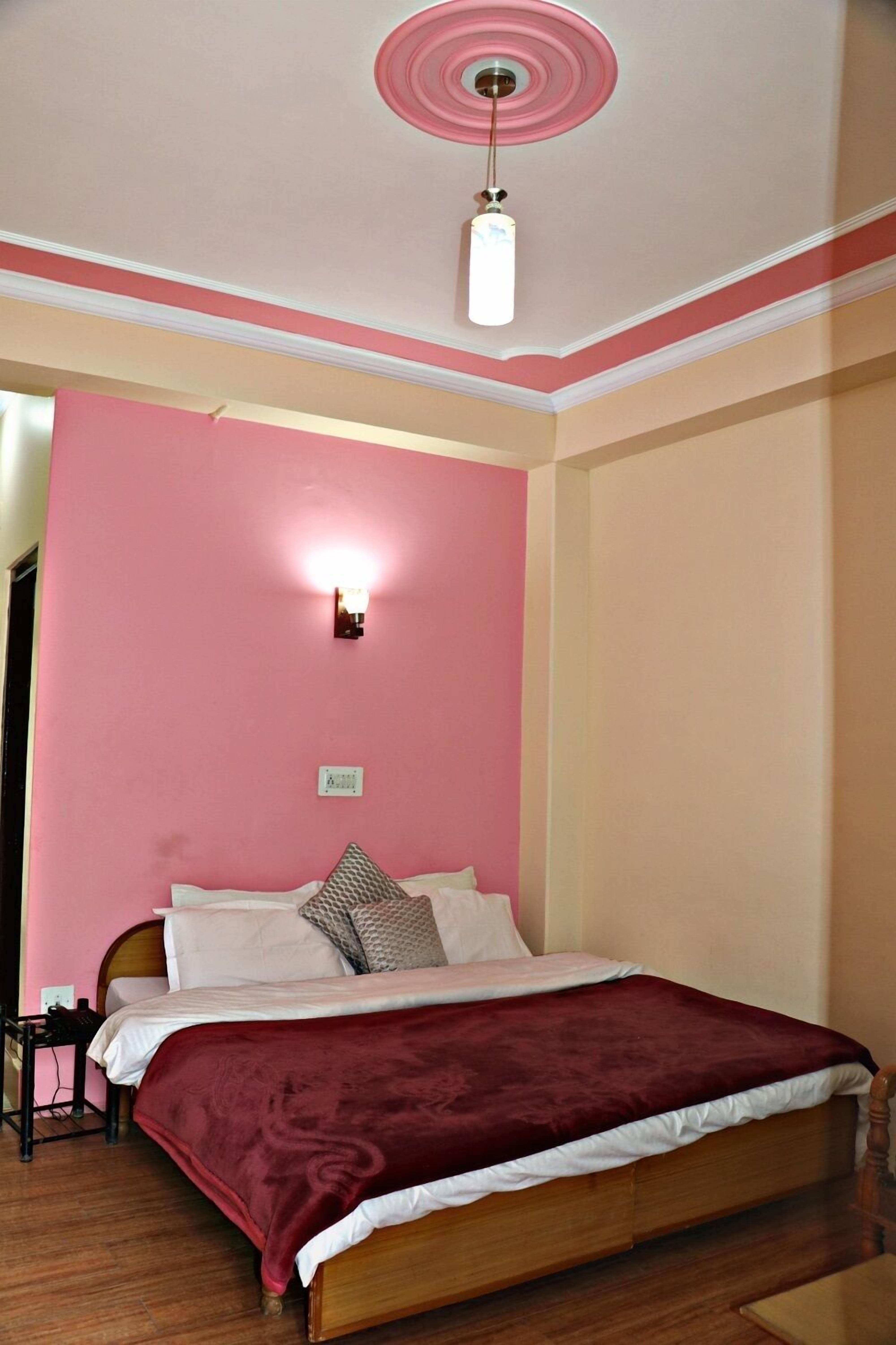 A bedroom with a wooden bed, pink walls, a ceiling fan, and a nightstand.