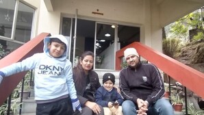 Una familia de cinco sentada en los escalones frente a un edificio con un letrero que dice 'Misty Meadows'.