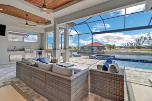 A spacious living area with a large window overlooking a swimming pool and a view of a residential area. - 706 NW 37th PL (Cape Coral)