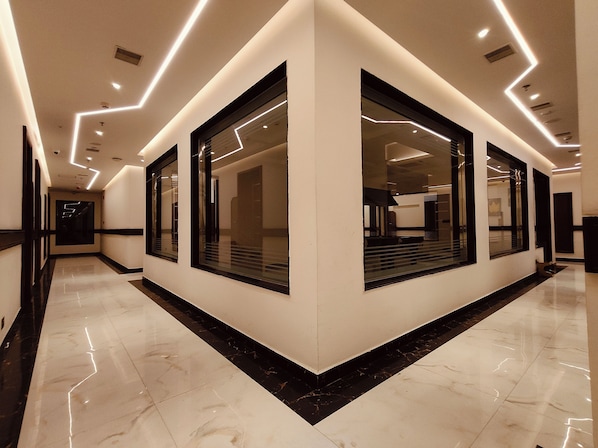 A modern hallway with reflective flooring, large windows, and recessed lighting.