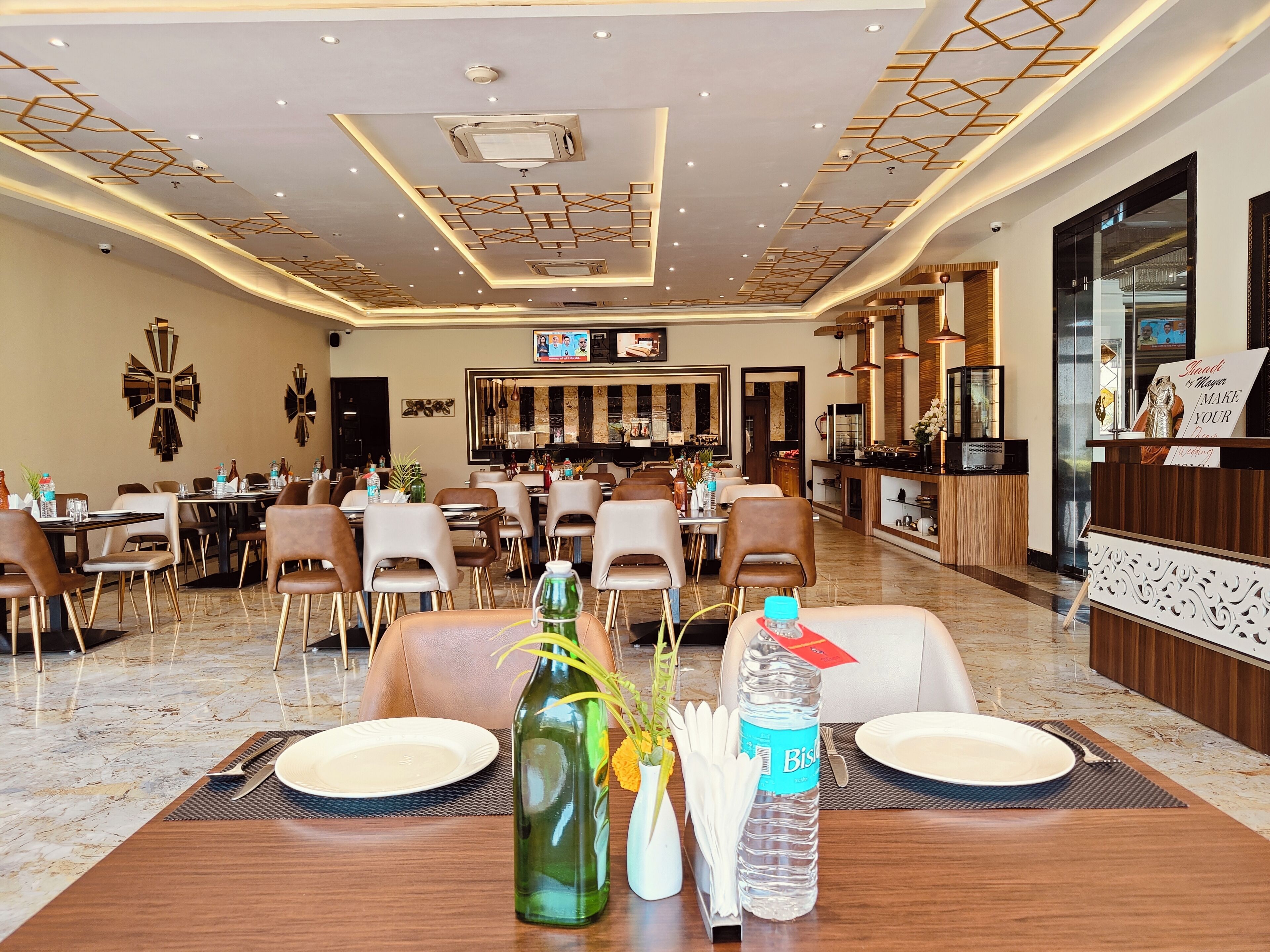 A hotel dining area with tables set for guests, a reception desk, and a bar area.