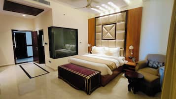 A modern hotel room with a large bed, a seating area, and a television.