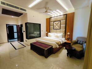 A modern hotel room with a large bed, a seating area, and a television.