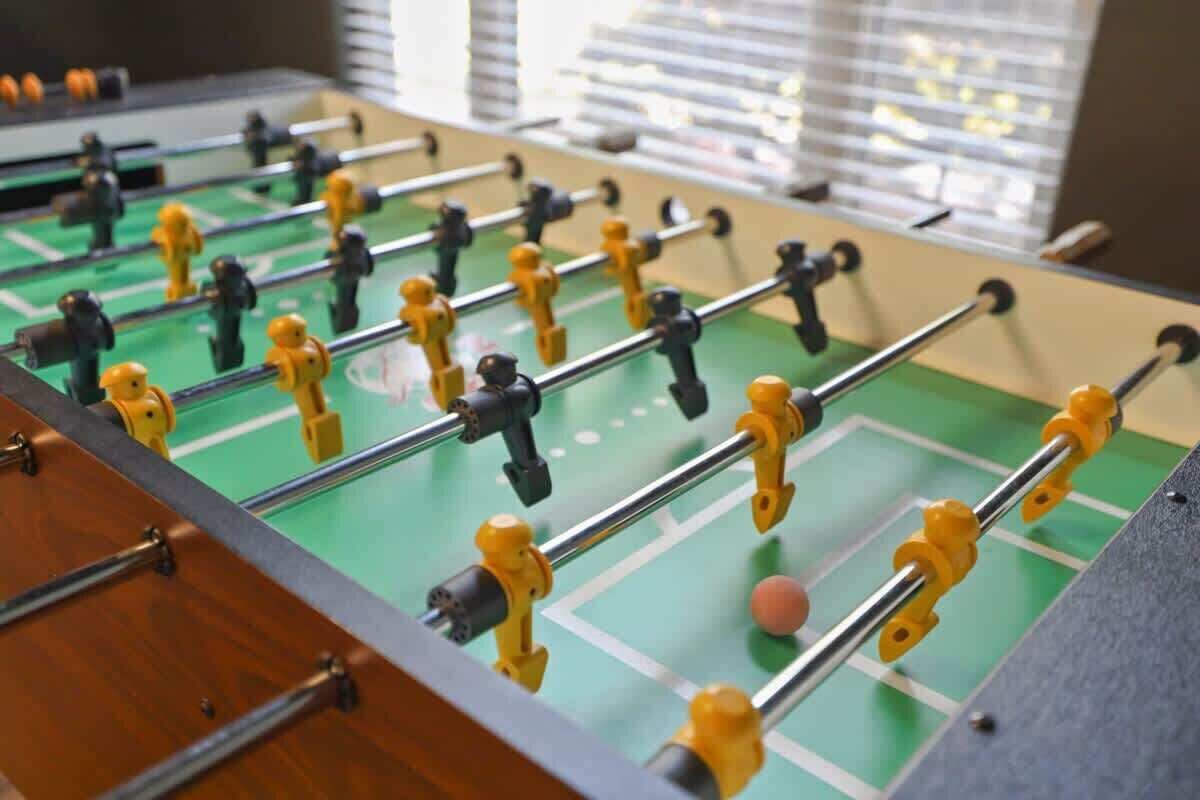 Una mesa de fútbolín con varias barras y figuras, sobre un campo de juego verde.