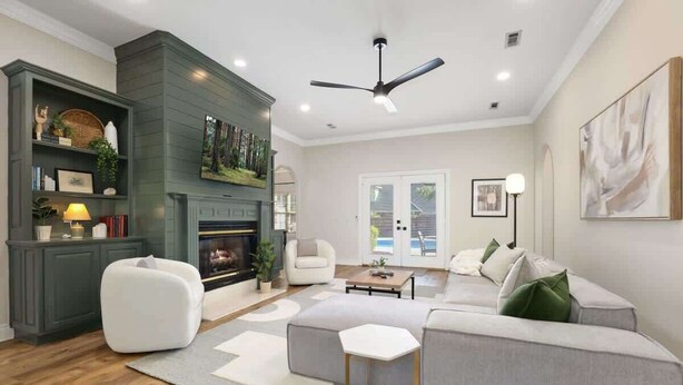 A modern living room with a fireplace, a ceiling fan, and a large painting on the wall. - Poolside Place - Game Room - MTB-Friendly (Bentonville)
