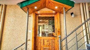 Una puerta de madera con un toldo verde y una barandilla de metal.