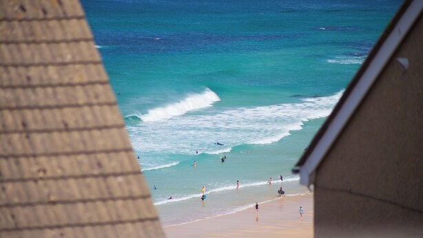 A beach view with waves, people, and a building structure. - Spernenwyn (St Ives)