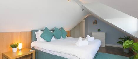 A bedroom with a bed, bedside table, and a nightstand with a lamp.