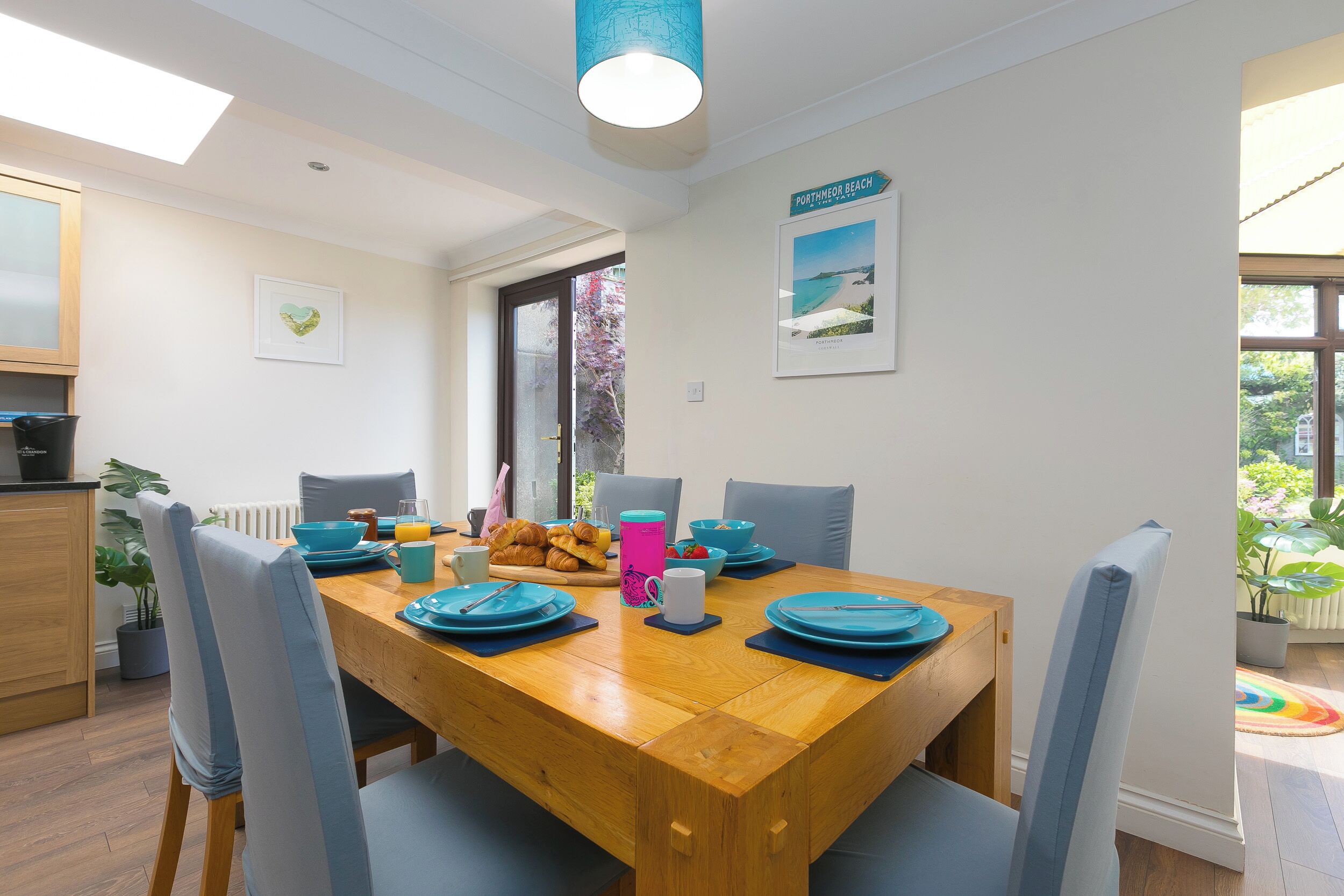 A dining area with a wooden table, blue chairs, and a view of the outdoors.