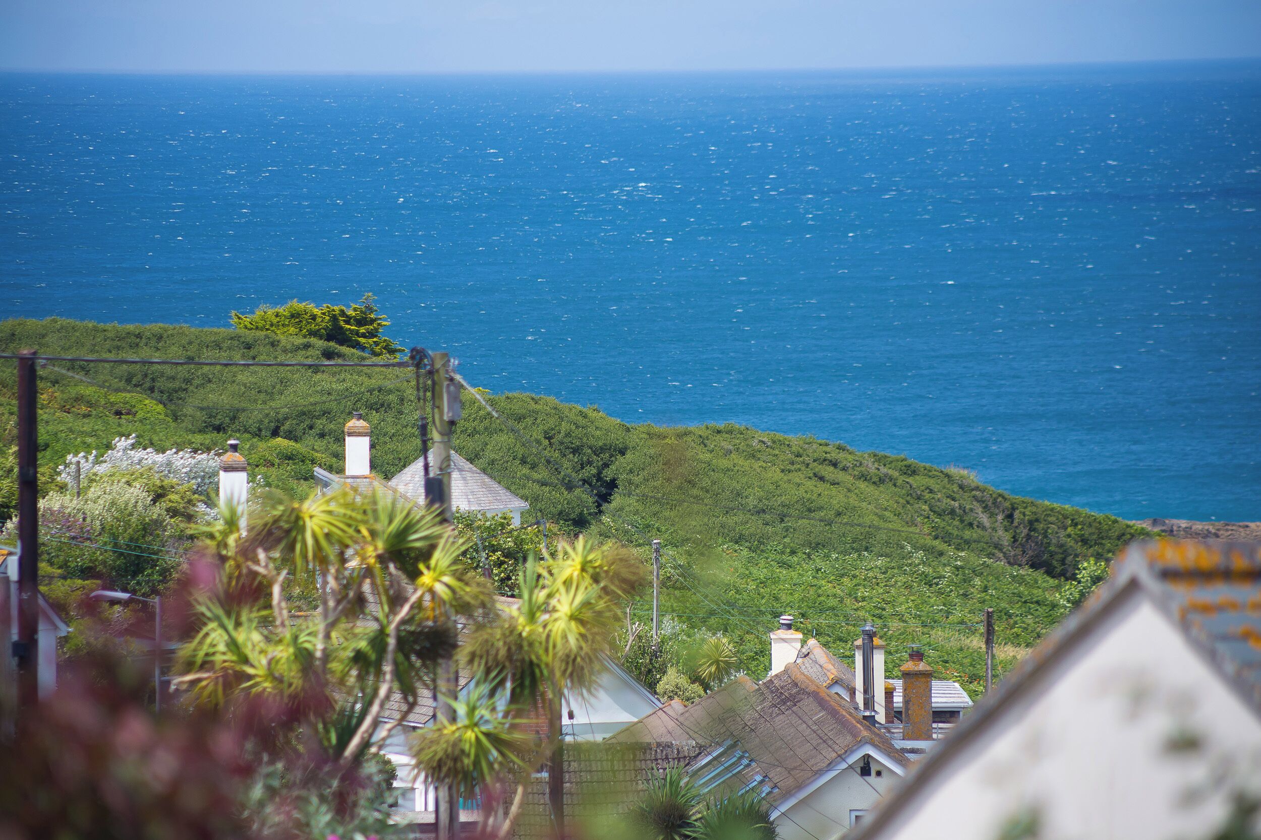 A coastal view with houses and greenery, overlooking the sea.