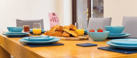 A breakfast table set with croissants, orange juice, and strawberries, with a pink sign reading "PRET".