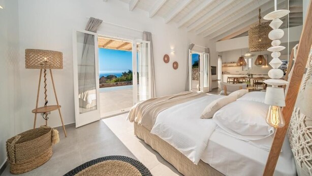 Un dormitorio espacioso con una cama grande, una lámpara colgante y vistas al exterior.