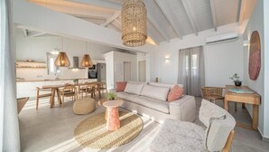Amplia sala de estar con techo alto, cocina moderna al fondo y un rincón de descanso acogedor.