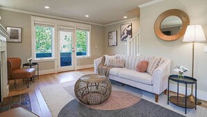A living room with a sofa, a round coffee table, a chair, and a lamp. - Designer 3BR Retreat | Steps from Stadiums (Seattle)