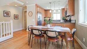 A modern kitchen with wooden cabinets, a central island, and pendant lighting. - Designer 3BR Retreat | Steps from Stadiums (Seattle)