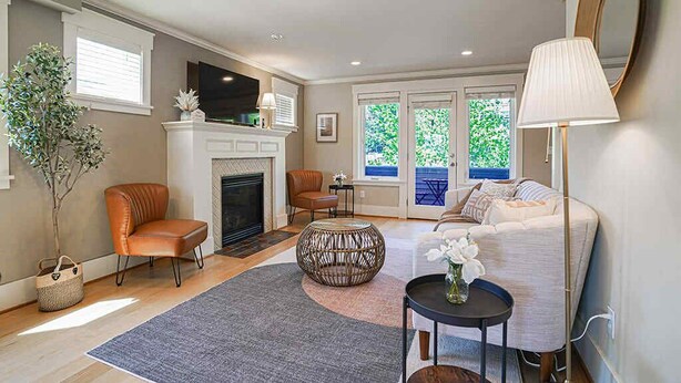 A living room with a fireplace, a sofa, a coffee table, and a lamp. - Designer 3BR Retreat | Steps from Stadiums (Seattle)