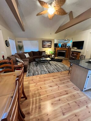 A living room with a sofa, coffee table, and a fireplace. There is a dining table with chairs and a kitchen area with a countertop. - Pet-friendly home featuring a private fenced backyard for safe outdoor fun (Ocean Pines)