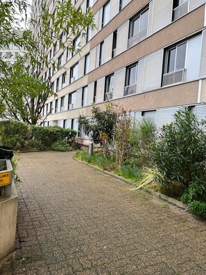 A building with multiple windows and a paved pathway leading to a gated entrance.