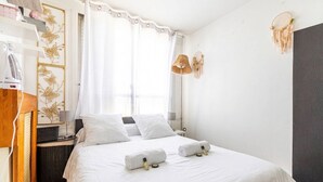 A hotel room with a bed, a desk, a chair, a lamp, and a wardrobe. - GuestReady - Glimpse of dawn in Asnières-sur-Seine (Asnières-sur-Seine)