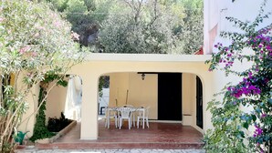 A patio with a table and chairs, surrounded by plants and a white wall. - Three-room apartment with sea view terrace, free private parking, beach at 200mt (Peducelli)