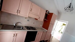 A kitchen with pink cabinets, a gas stove, and a sink. - Three-room apartment with sea view terrace, free private parking, beach at 200mt (Peducelli)
