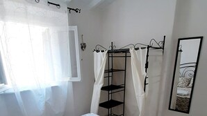 A bedroom with a large bed, a metal shelf unit, and a mirror on the wall. - Three-room apartment with sea view terrace, free private parking, beach at 200mt (Peducelli)