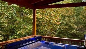Un bain à remous sur une terrasse en bois, avec vue sur les arbres.