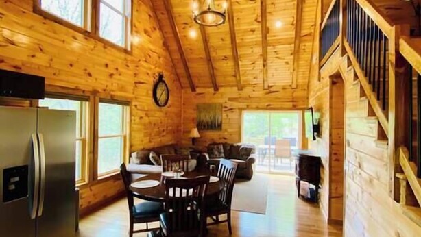 L’intérieur d’une cabane en bois comprend une cuisine, un coin repas et un escalier.